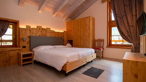 Um quarto de madeira com uma cama, uma cadeira, uma escrivaninha e uma televisão.