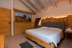 A wooden bedroom with a bed, a painting, and a window.
