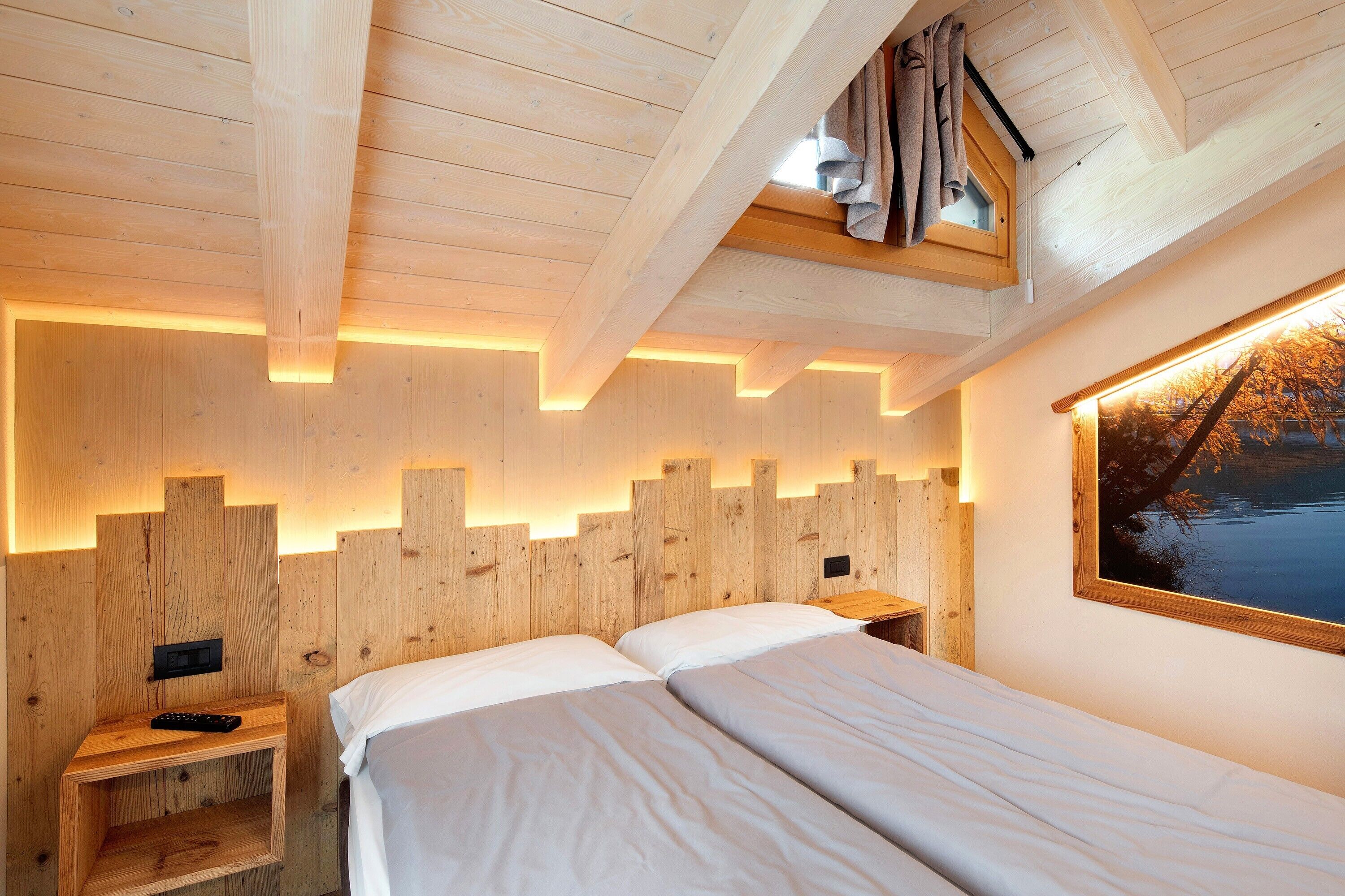 A wooden-paneled room with a bed, bedside tables, and a window with a view.