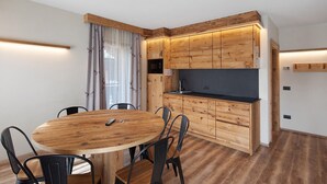 Una cocina compacta con armarios de madera, una mesa redonda para comer y sillas negras.