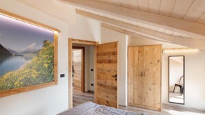 Un dormitorio con cama, armario de madera y un cuadro grande de un paisaje en la pared.