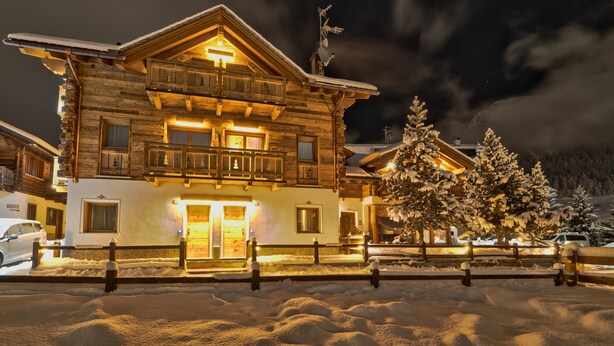A multi-story wooden lodge with balconies, a snow-covered landscape, and a clear night sky. - Apartment 'Chalet Leur Gusja Golp Trilocale' with Mountain View, Shared Garden and Wi-Fi (Livigno)