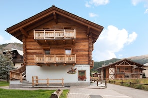 A wooden chalet with a balcony, a stone staircase, and a sign reading 'Chalet La Gop.'