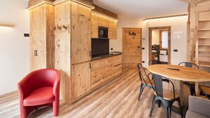 A modern kitchen with wooden cabinetry and a dining area with a round table and chairs. - Apartment 'Chalet Leur Gusja Golp Trilocale' with Mountain View, Shared Garden and Wi-Fi (Livigno)