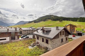 A rustic mountain lodge with stone buildings, a wooden deck, and a view of a ski slope.