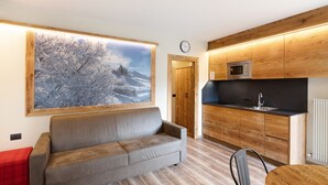 Een moderne keuken met houten kastjes, een magnetron en een klok aan de muur.