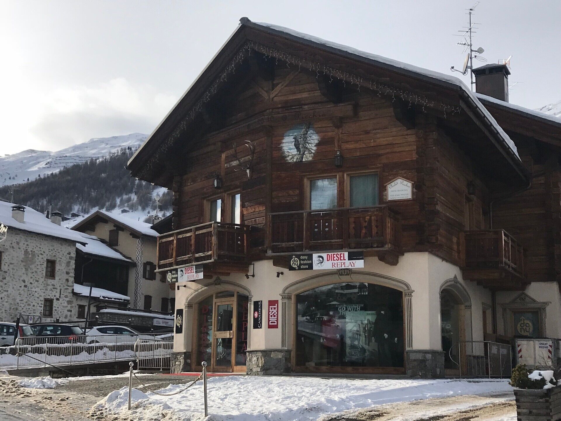 A wooden building with a balcony, a sign for 'DIESEL REPLAY,' and a large window.