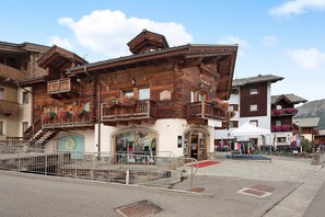 A wooden building with balconies, a staircase, and a storefront with clothing items. - Apartment 'Chalet Picchio Bilocale' with Mountain View, Balcony and Wi-Fi (Livigno)