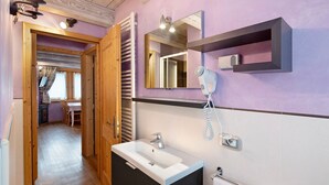 Ein Badezimmer mit Waschbecken, Spiegel, Handtuchhalter und einem Fön.