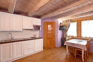 Una cocina con armarios de madera, un lavamanos y una mesa de comedor con sillas.