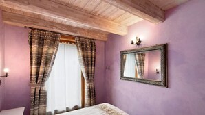 Ein Schlafzimmer mit Bett, Vorhängen, einem Spiegel und einer Lampe.