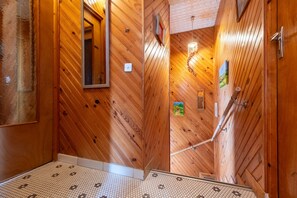 Un intérieur en bois, avec un sol carrelé, un miroir et un tableau accroché au mur.