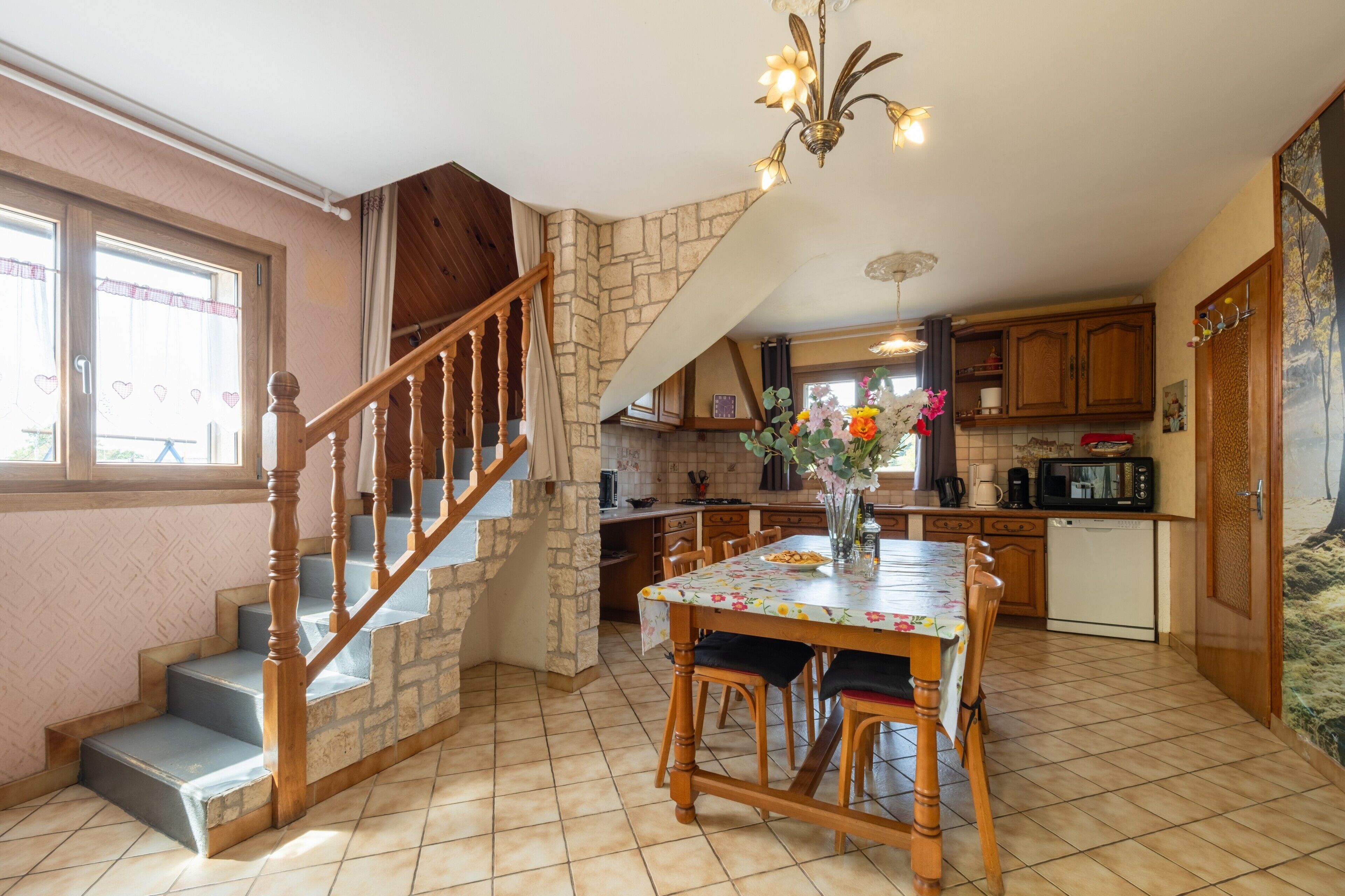 A kitchen with a dining table, chairs, a staircase, and a kitchen island.