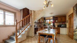 A kitchen with a dining table, chairs, a staircase, and a kitchen island.