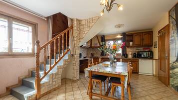 A kitchen with a dining table, chairs, a staircase, and a kitchen island.