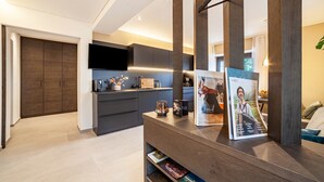 A modern kitchen with dark cabinetry, a flat-screen TV, and a magazine on the counter. - Apartment "Maja" with Mountain View, Private Garden and Wi-Fi (San Martino In Passiria)