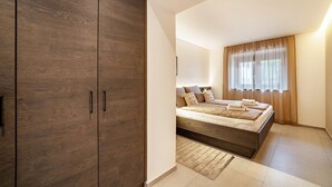 A bedroom with a large wardrobe, a bed with a headboard, and a window with curtains. - Apartment "Maja" with Mountain View, Private Garden and Wi-Fi (San Martino In Passiria)