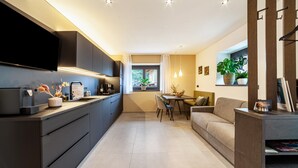 A modern kitchen with a flat-screen TV, dark cabinetry, and a dining area with a table and chairs. - Apartment "Maja" with Mountain View, Private Garden and Wi-Fi (San Martino In Passiria)