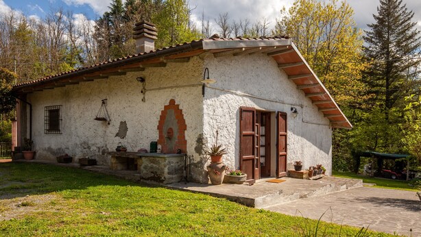 Un bâtiment rustique avec un toit en pente, un petit porche et une arche en briques.