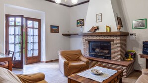 Un salon avec une cheminée, un fauteuil en cuir et un coin repas comprenant une table et des chaises.