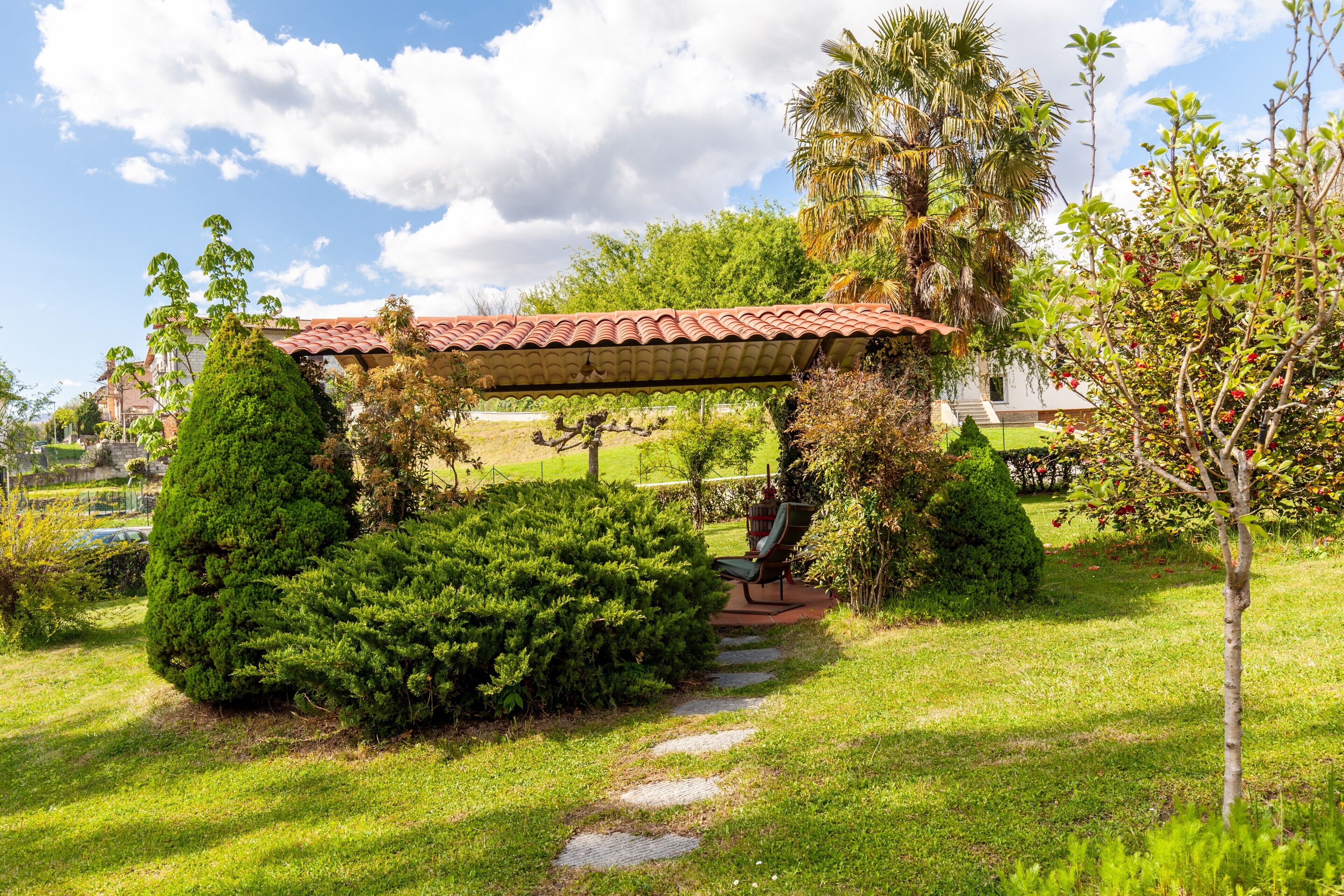 A garden with a pergola, a pathway, and a bench.