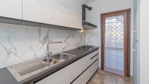Una cucina moderna con schienale in marmo, lavello in acciaio inossidabile e piano cottura a gas.