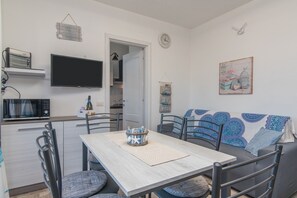 A modern kitchen with a flat-screen TV, a microwave, and a dining area with a table and chairs.