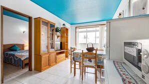 Un espacio habitable compacto con kitchenette, comedor y dormitorio.