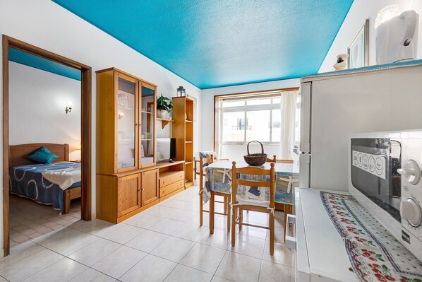 Un espace de vie compact comprenant une kitchenette, un coin repas et une chambre.