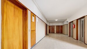 Un pasillo con puertas de madera, un extintor y suelo de baldosas.