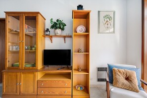 A living room with a wooden entertainment center, a television, a plant, and a framed artwork on the wall.