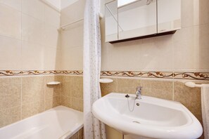 Une salle de bain avec une baignoire, un lavabo, un miroir et un rideau de douche.