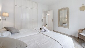 A hotel room with a bed, a chair, a wardrobe, and a mirror. - Holiday Home 'La Villa La Palma- 2 Dormitorios' with Sea View, Wi-Fi and Air Conditioning (Dos Pinos)