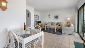 A living room with a glass table, white chairs, a sofa, and a coffee table. - Holiday Home 'La Villa La Palma- 2 Dormitorios' with Sea View, Wi-Fi and Air Conditioning (Dos Pinos)