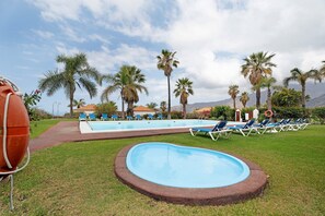 Une piscine avec des chaises longues, des palmiers et une bouée de sauvetage.