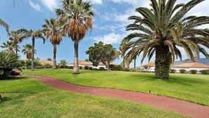 A well-maintained lawn with palm trees and a red pathway. - Holiday Home 'La Villa La Palma- 2 Dormitorios' with Sea View, Wi-Fi and Air Conditioning (Dos Pinos)