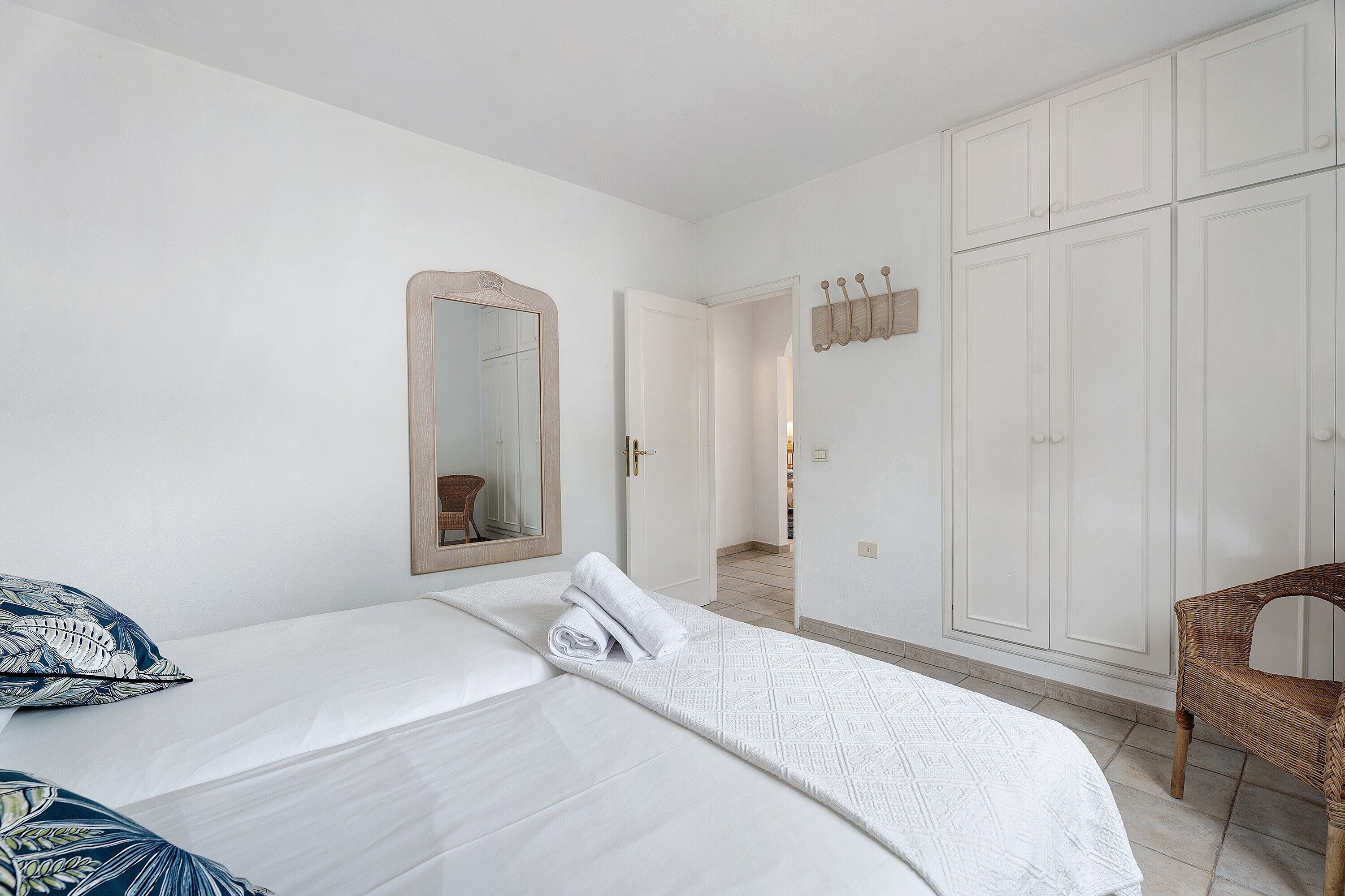 Een slaapkamer met een bed, een stoel, een kledingkast en een spiegel.