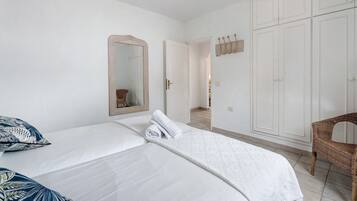 Een slaapkamer met een bed, een stoel, een kledingkast en een spiegel.