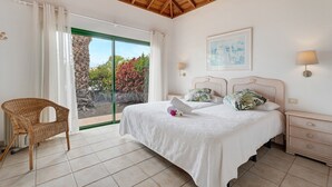 Une chambre à coucher comprenant un lit, une chaise, une table de chevet, une lampe et une vue sur l’extérieur.