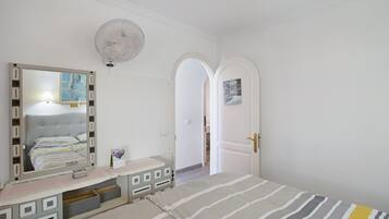 Une chambre à coucher avec un lit, une commode, un miroir et une porte en arc de cercle.