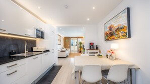 A modern kitchen with white cabinets, a black countertop, and a dining area with a table and chairs. - Apartment 'Lagomar' with Private Terrace, Wi-Fi and Air Conditioning (Alcudia)