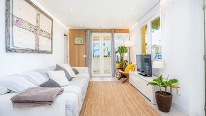 A modern living room with a sofa, a TV, a potted plant, and a sliding glass door leading to a balcony. - Apartment 'Lagomar' with Private Terrace, Wi-Fi and Air Conditioning (Alcudia)
