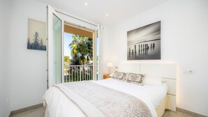 A bedroom with a bed, a nightstand, a window, and a painting on the wall. - Apartment 'Lagomar' with Private Terrace, Wi-Fi and Air Conditioning (Alcudia)