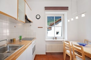 Une cuisine équipée d’un évier, d’une cuisinière et d’une fenêtre donnant sur une maison.
