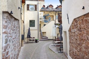 A narrow cobblestone street with outdoor seating and a staircase leading to a building. - Holiday Apartment "Wally" with Mountain View, Balcony & Wi-Fi (Appiano)