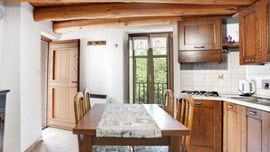 A kitchen with wooden cabinets, a dining table with chairs, and a window with curtains.