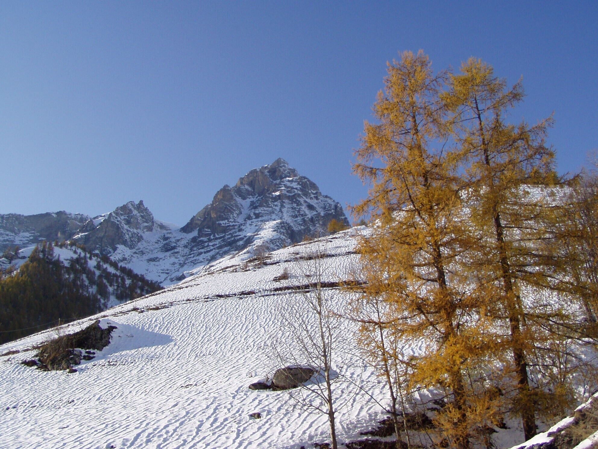 A mountainous landscape with snow-covered slopes and a clear sky.