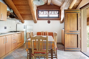 Une cuisine avec des meubles de rangement en bois, une table à manger avec des chaises et une fenêtre avec des rideaux.