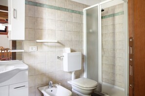 Un baño con inodoro, bidé, lavamanos y cabina de ducha.