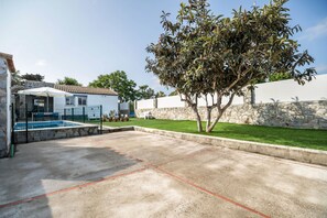Un espace piscine agrémenté d’un mur en pierre, d’un arbre et d’un bâtiment doté d’un toit en tuiles.